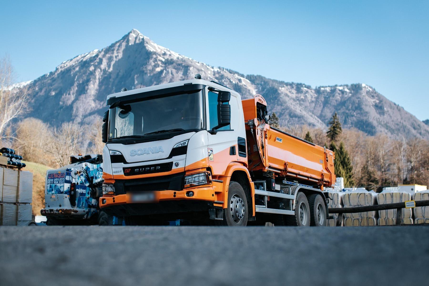 Camion benne orange TRANS MIS sur un chantier de la Vallée de l’Arve, au pied des montagnes
