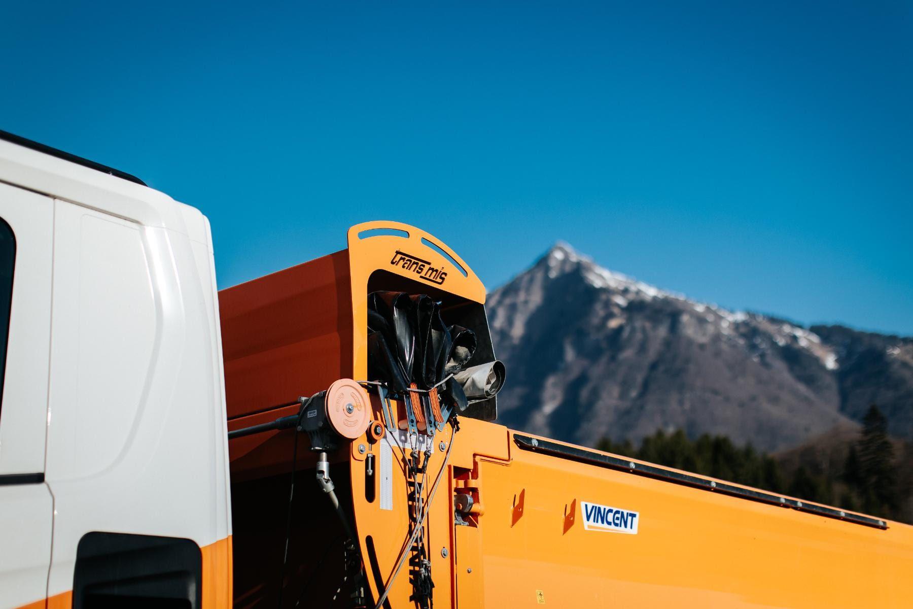 Benne orange VINCENT d’un camion TRANS MIS, devant les montagnes de la Vallée de l’Arve