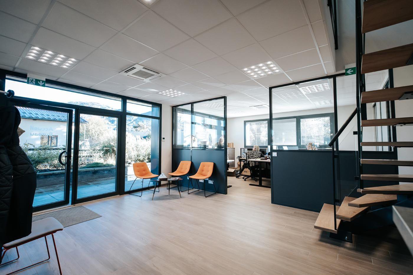 Accueil et bureaux de TRANS MIS : espace vitré, sièges orange et escalier bois